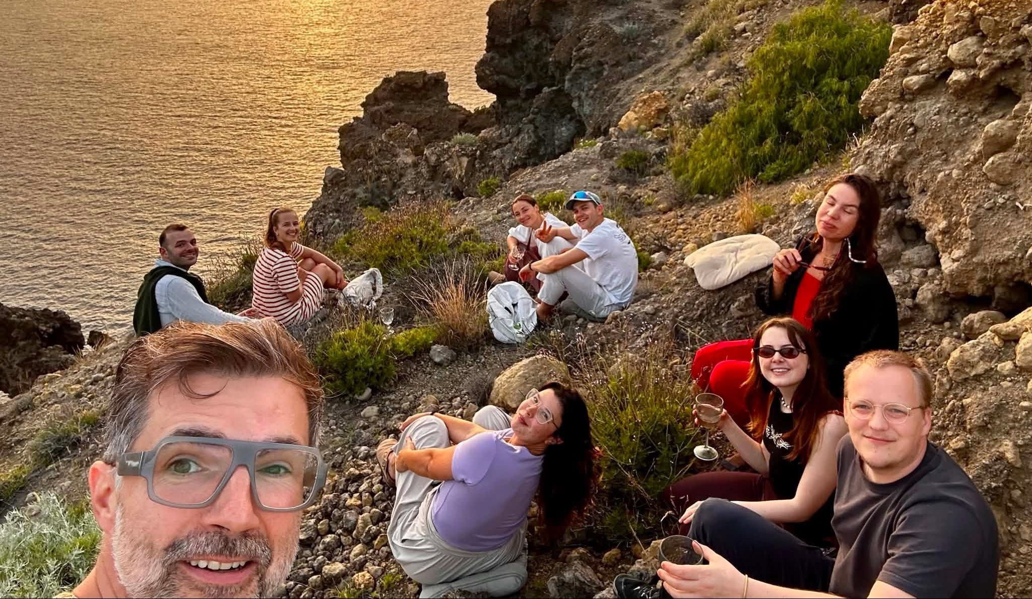 Group of people enjoying a sunset at a scenic coastal location.